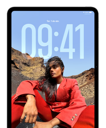 Um iPad mostrando a Tela Bloqueada com números da hora grandes aparecendo atrás da imagem de uma pessoa sentada