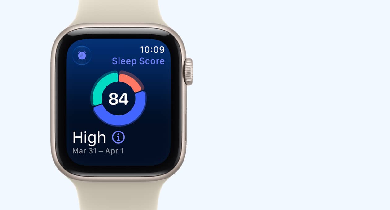Apple Watch SE 3, aluminiumboett i färgen stjärnglans, på skärmen visas ett cirkeldiagram med sömnpoäng, höger utsida, Digital Crown, sportband i färgen sand (ljusbrun)